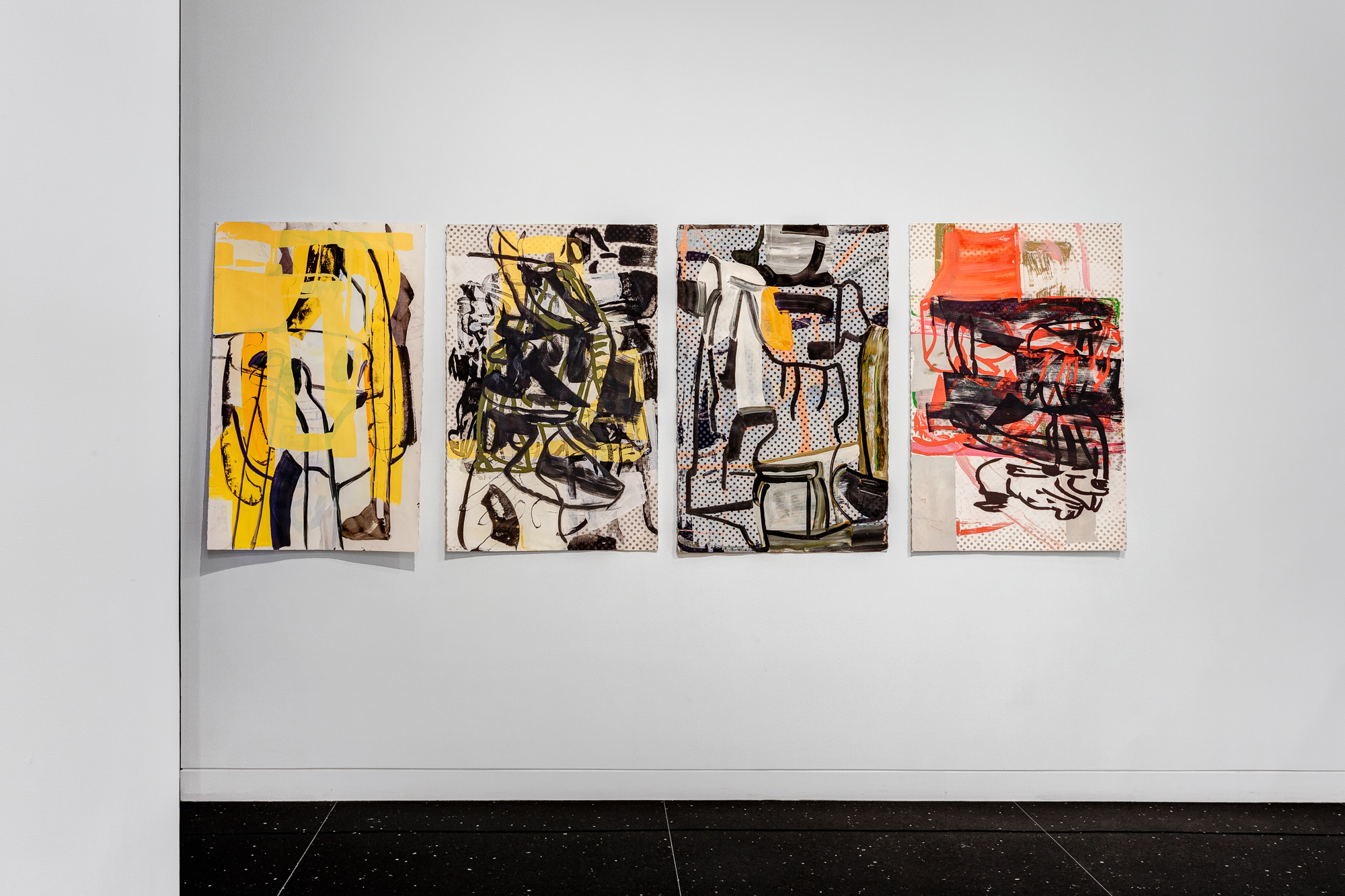 Four abstract paintings on paper aligned on a white gallery wall.