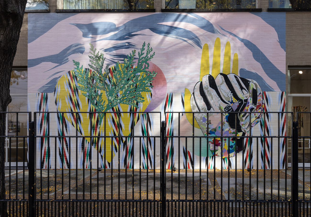 Mural behind a black fence featuring a heart and clasped hands.