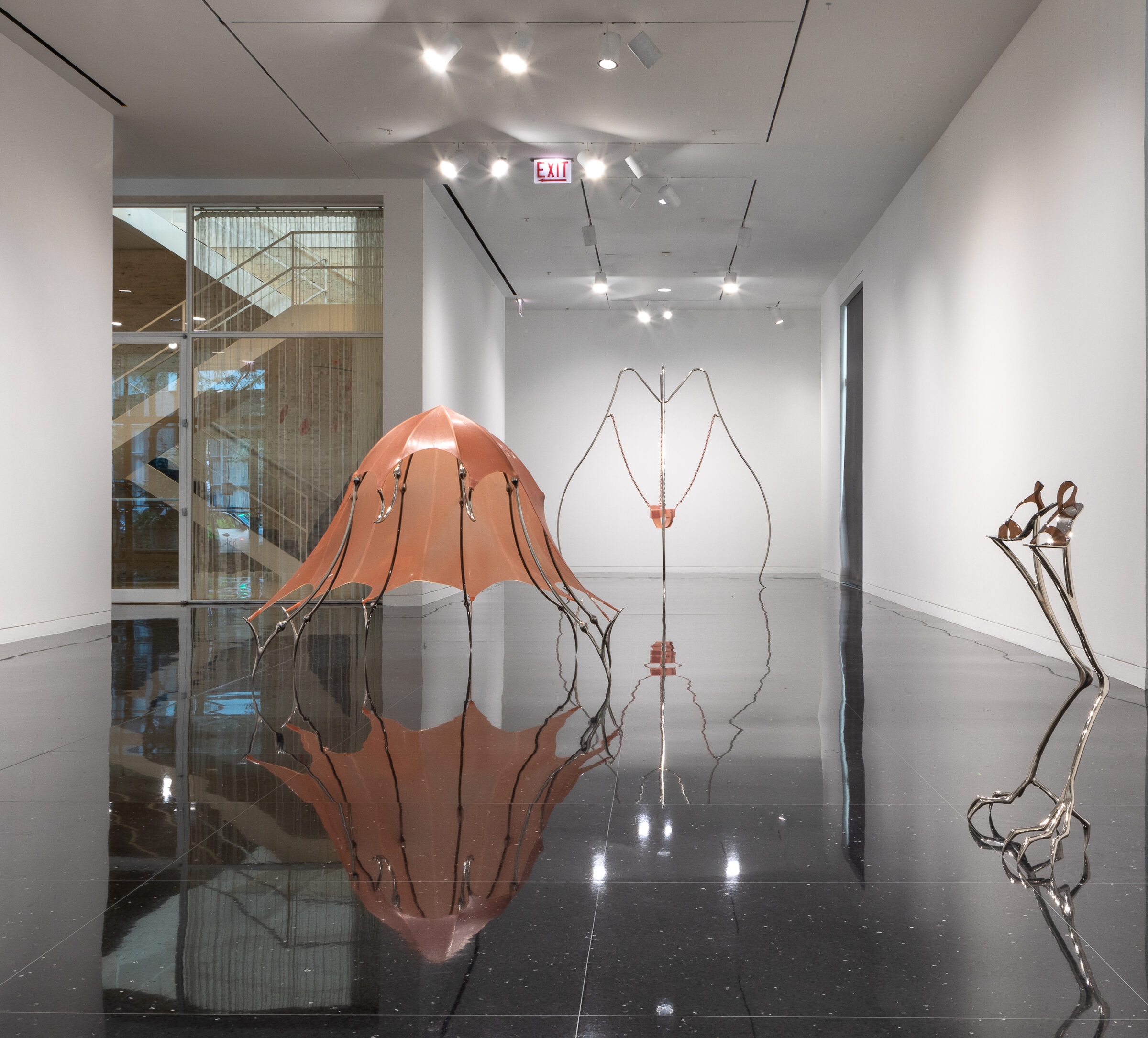 A white gallery space with several large sculptures made of pale pink latex and steel to form animal and insect-like shapes.