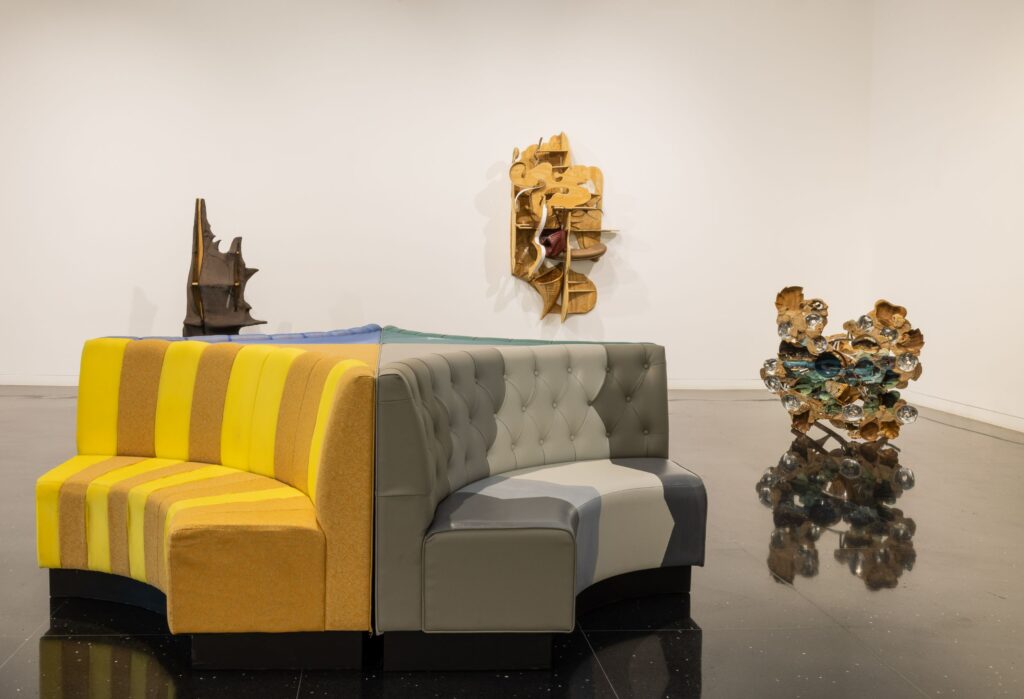 The Arts Club of Chicago east gallery installation view prominently featuring exhibition booth furniture, a sculptural chair, and wall works, Jessi Reaves: All possessive lusts dispelled.