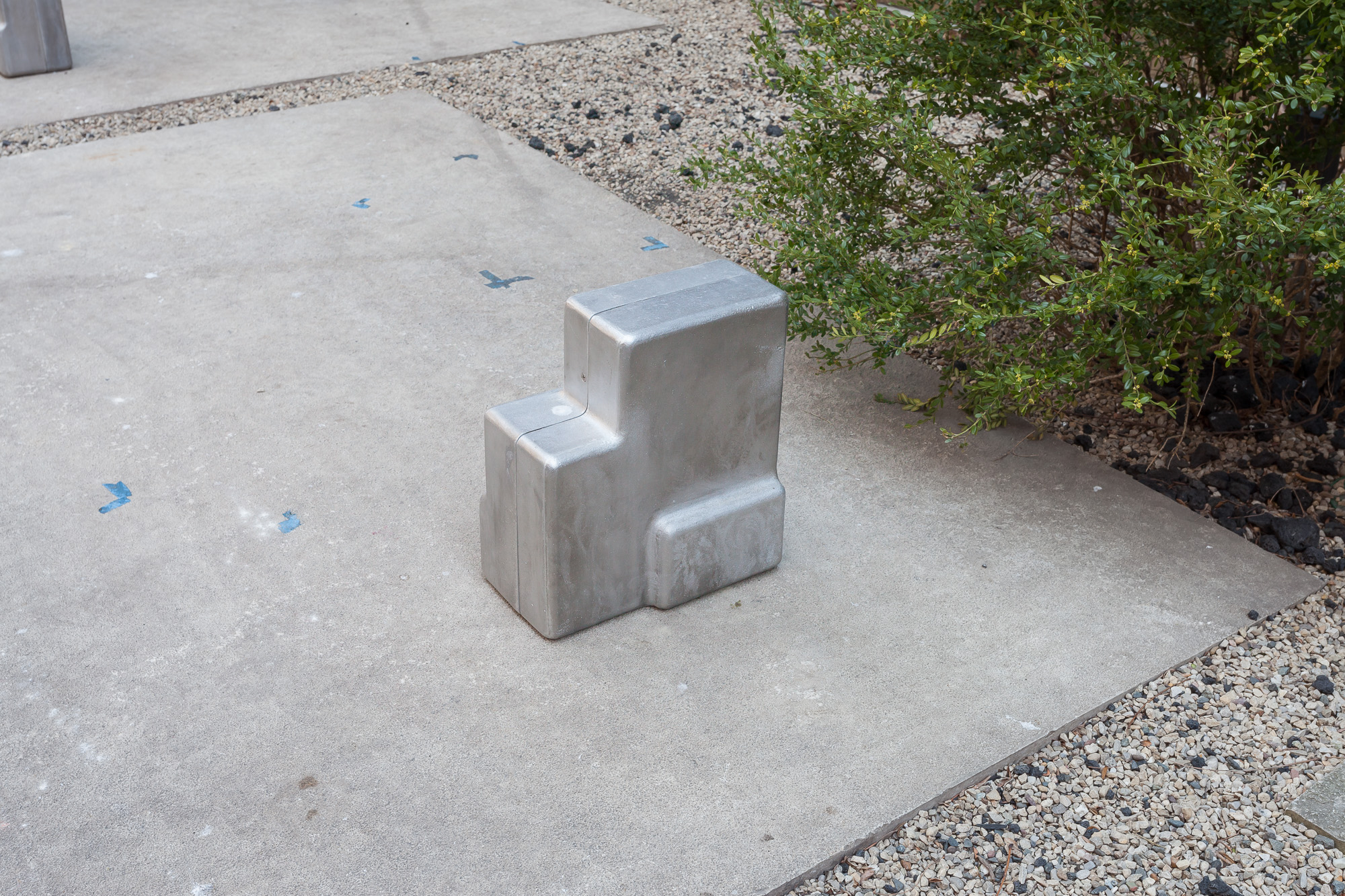 A small cast metal sculpture resembling blocks or stair steps placed on the ground.
