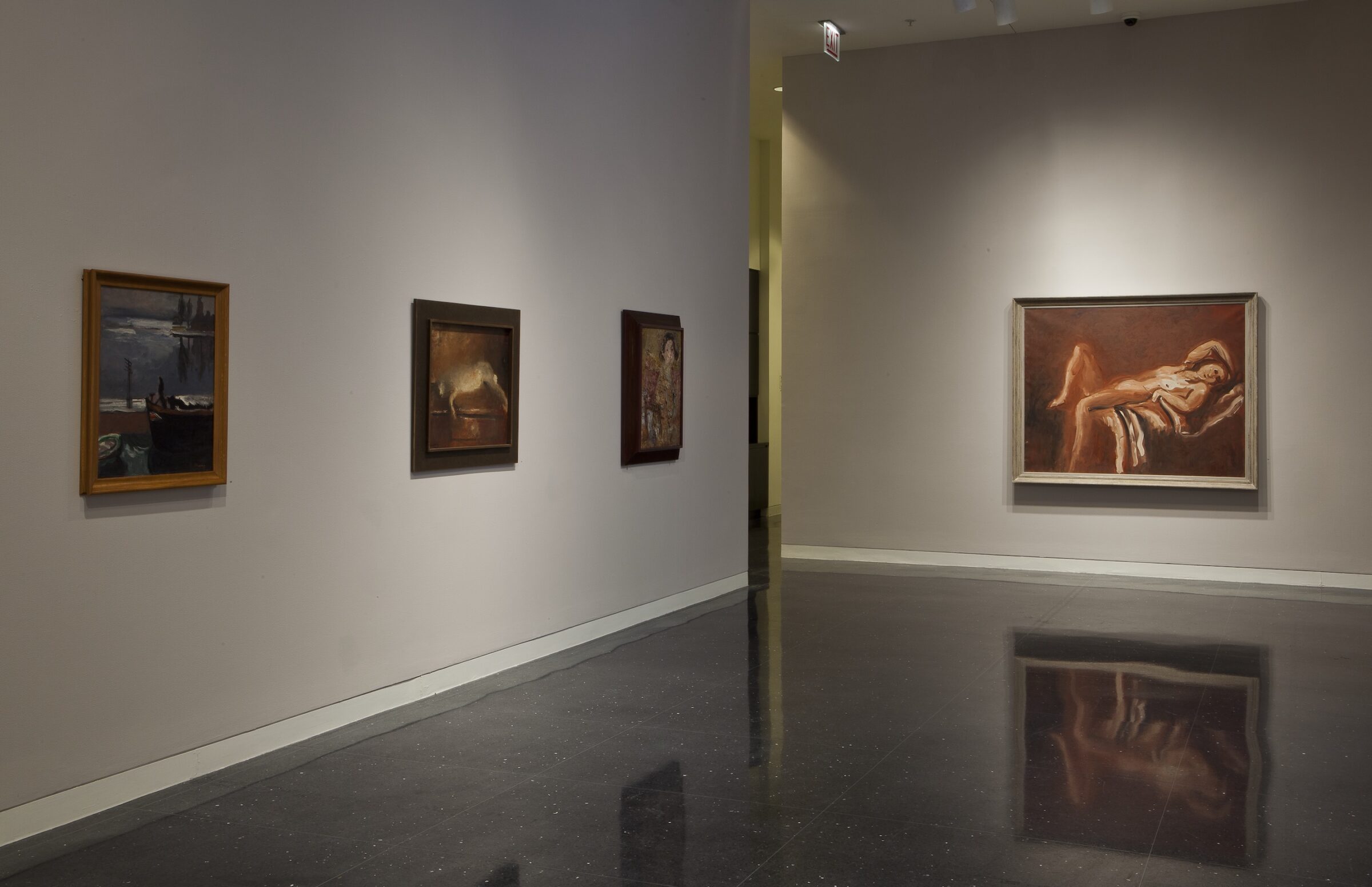 Four framed paintings of varying subjects hang in a row on a beige gallery wall. The largest painting furthest right to the viewer depicts a reclining nude.