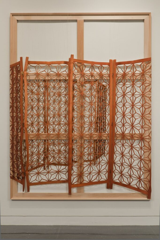 A burnt orange decorative screen laid on top of a wooden frame shaped like a four pane window.