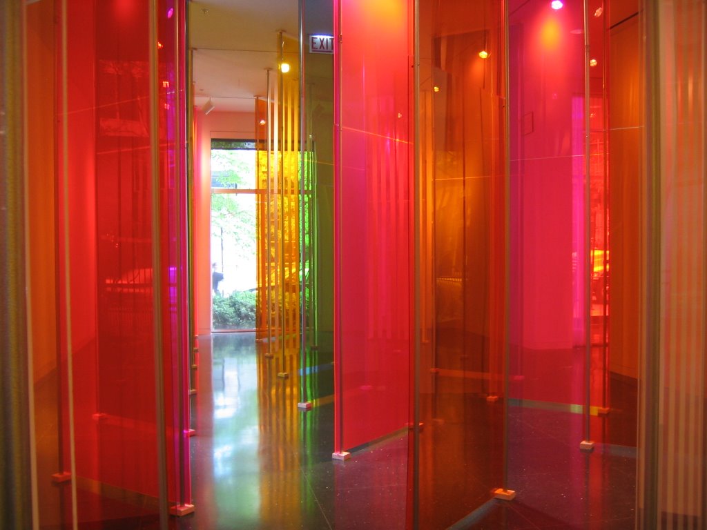 A rainbow of colored and transparent plexiglass walls installed inside a gallery.