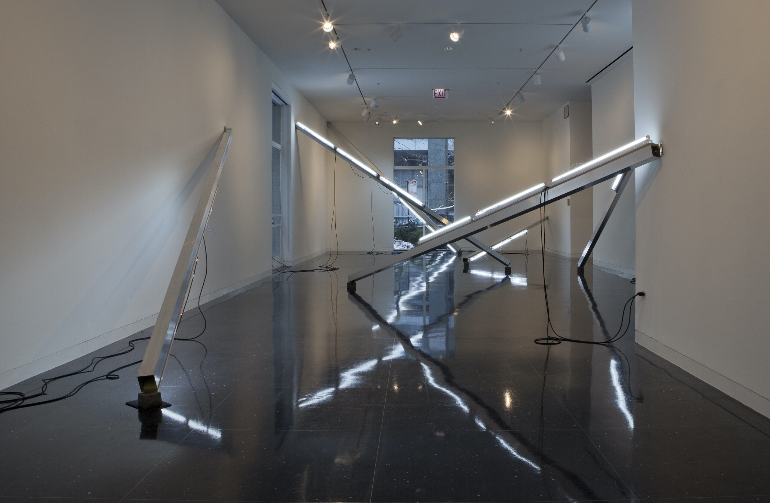 Long strips of lighting leaning on the walls create a maze through a gallery space.