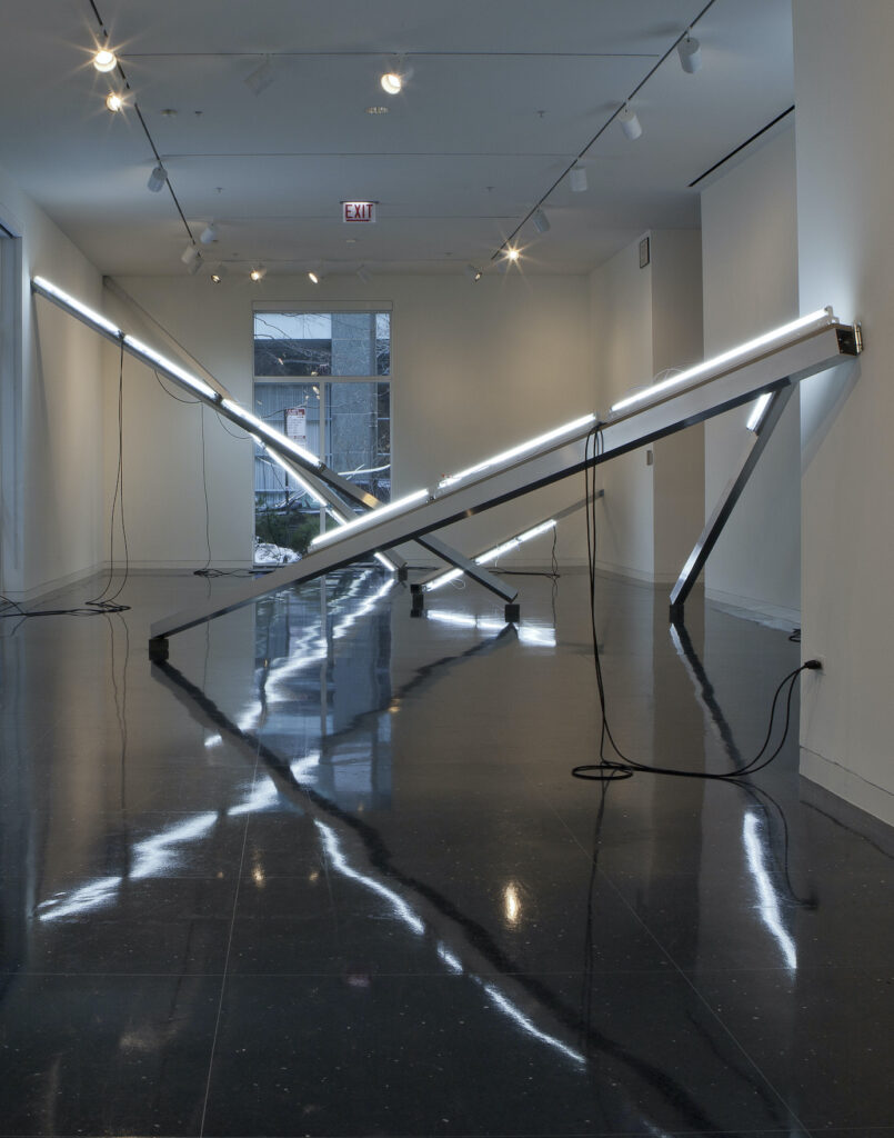 Long strips of lighting leaning on the walls create a maze through a gallery space.