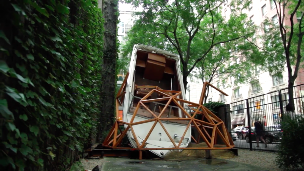 A life-sized motorboat is suspended within a geometric half circle within an outdoor patio.