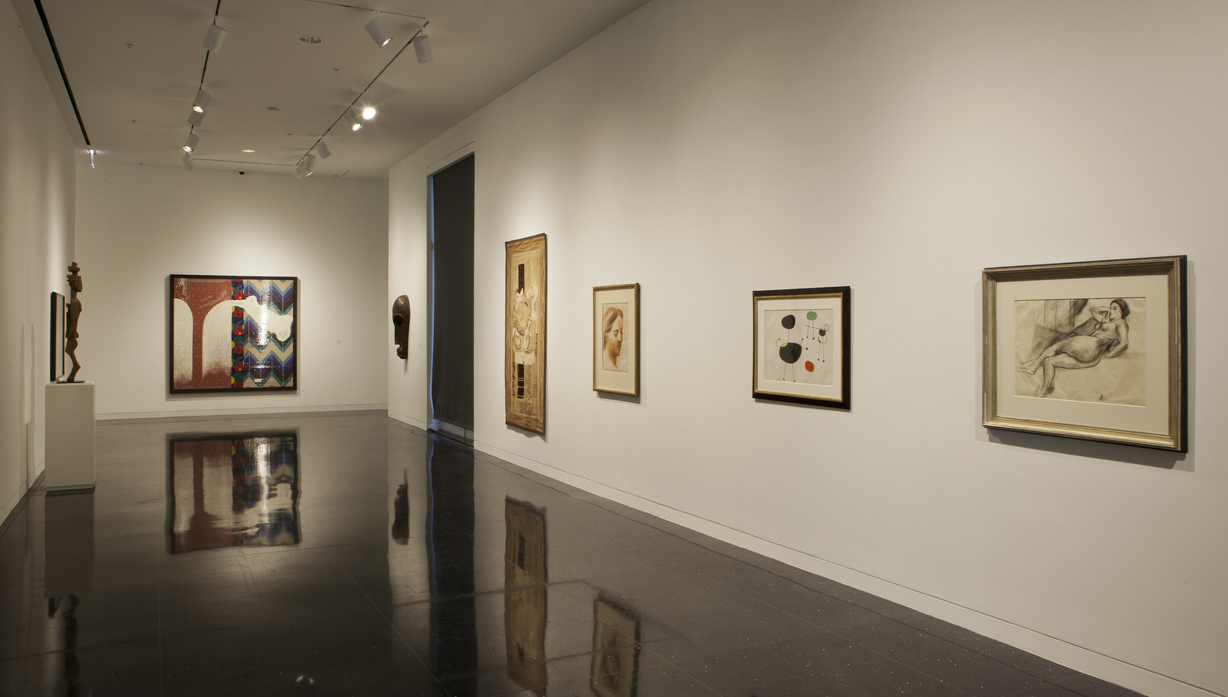 A white walled gallery featuring drawings by Matisse, Miro, and Picasso from The Arts Club's permanent collection, arranged in a horizontal line on the wall.