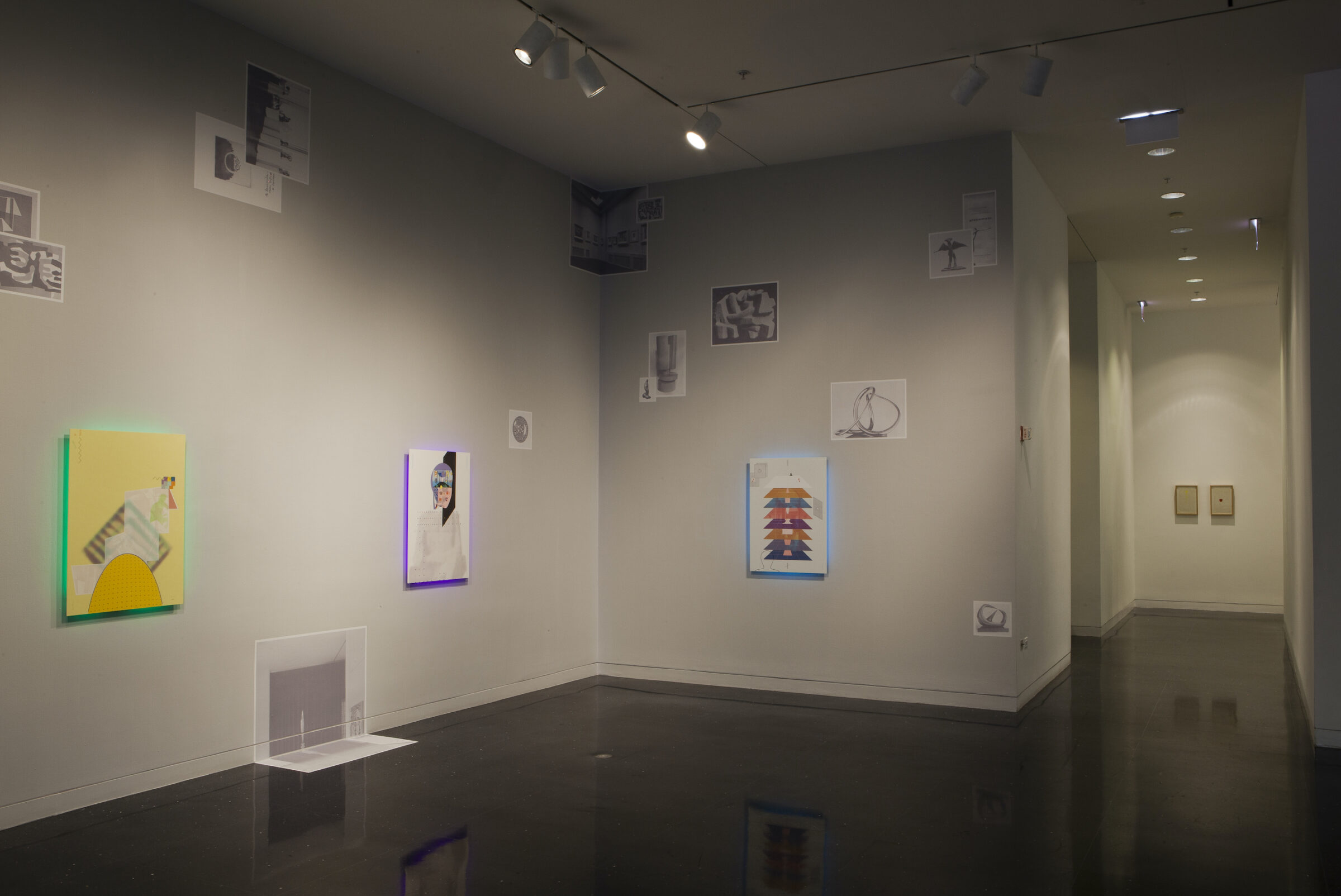 A dimly lit gallery space with colorful drawings hung on the walls.