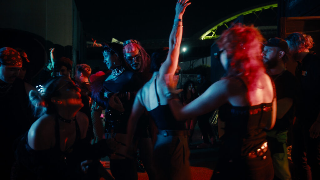 a scene of a group of people dancing in a dark club with red lighting